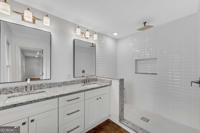 bathroom with wood-type flooring, vanity, and a tile shower