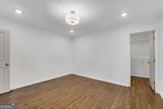 unfurnished bedroom featuring a closet, a spacious closet, and dark hardwood / wood-style floors