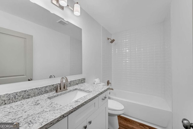 full bathroom with tiled shower / bath combo, vanity, wood-type flooring, and toilet