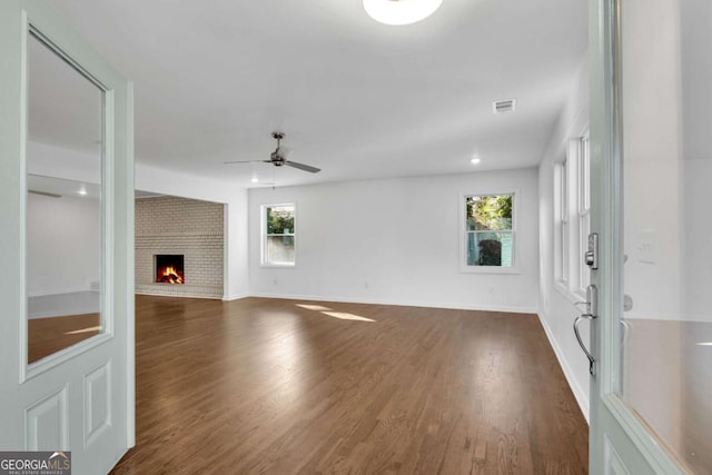 unfurnished living room featuring dark hardwood / wood-style flooring, ceiling fan, and a fireplace