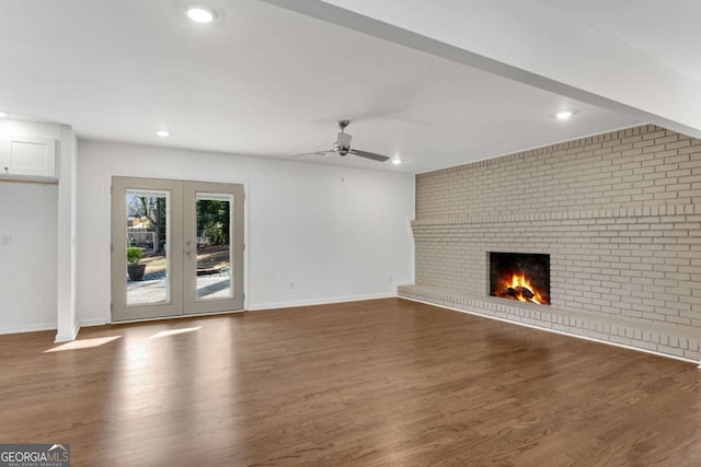 unfurnished living room featuring a fireplace, dark hardwood / wood-style floors, and ceiling fan