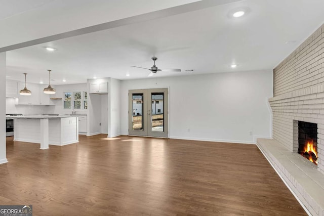 unfurnished living room with dark hardwood / wood-style floors, ceiling fan, a fireplace, and sink