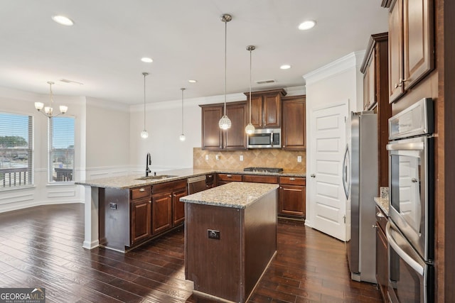 kitchen featuring a peninsula, a sink, decorative light fixtures, and stainless steel appliances