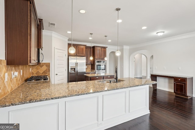 kitchen with stainless steel appliances, arched walkways, pendant lighting, and a sink