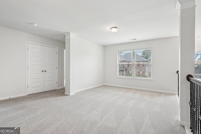 unfurnished room featuring decorative columns, visible vents, baseboards, and light colored carpet