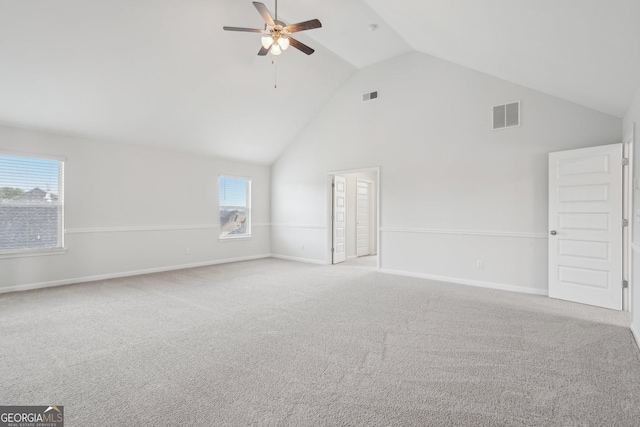 unfurnished living room featuring light colored carpet, visible vents, ceiling fan, high vaulted ceiling, and baseboards