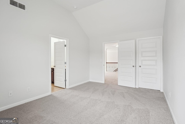 unfurnished bedroom featuring lofted ceiling, light carpet, visible vents, and baseboards