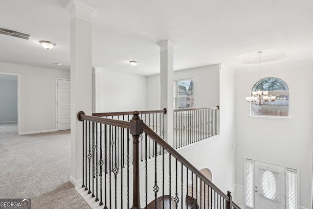 hallway featuring light colored carpet, a notable chandelier, visible vents, and an upstairs landing