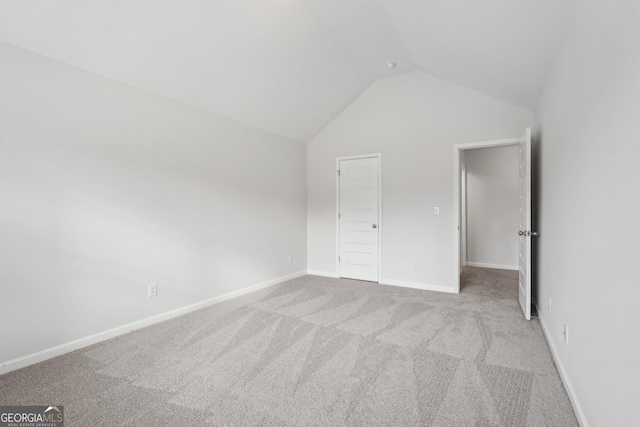 unfurnished bedroom with lofted ceiling, light carpet, and baseboards