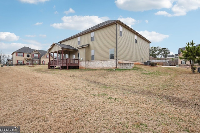 rear view of house featuring a lawn and a wooden deck