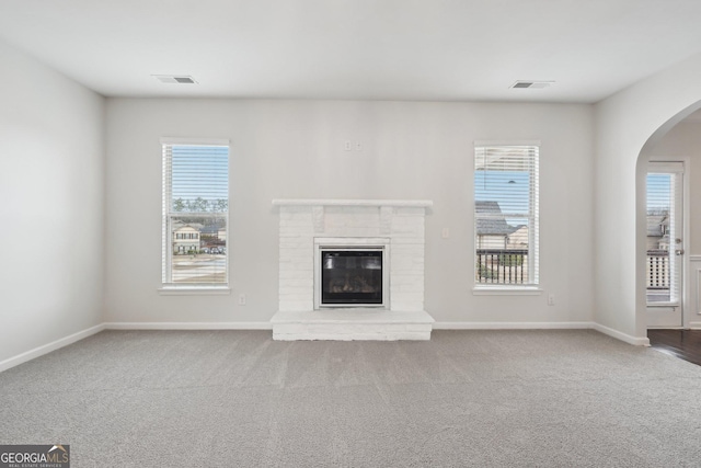 unfurnished living room featuring carpet floors, visible vents, and a wealth of natural light