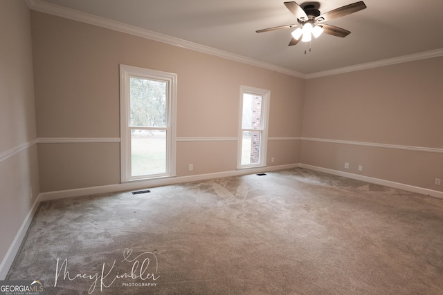 empty room with ornamental molding, carpet, and ceiling fan