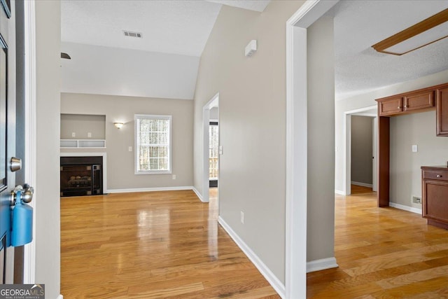 foyer featuring lofted ceiling, a textured ceiling, and light hardwood / wood-style floors