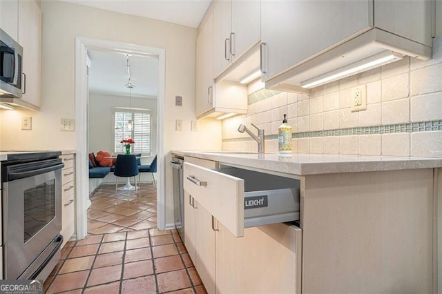 kitchen with sink, light tile patterned floors, white cabinetry, stainless steel appliances, and tasteful backsplash