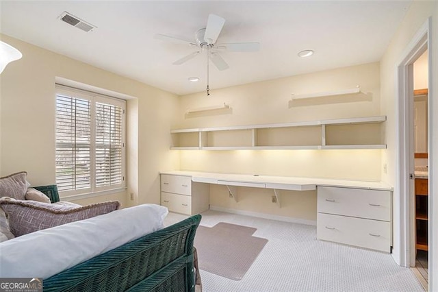 carpeted bedroom featuring built in desk and ceiling fan