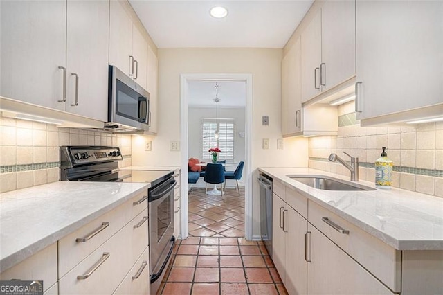 kitchen featuring sink, light stone counters, tasteful backsplash, stainless steel appliances, and white cabinets