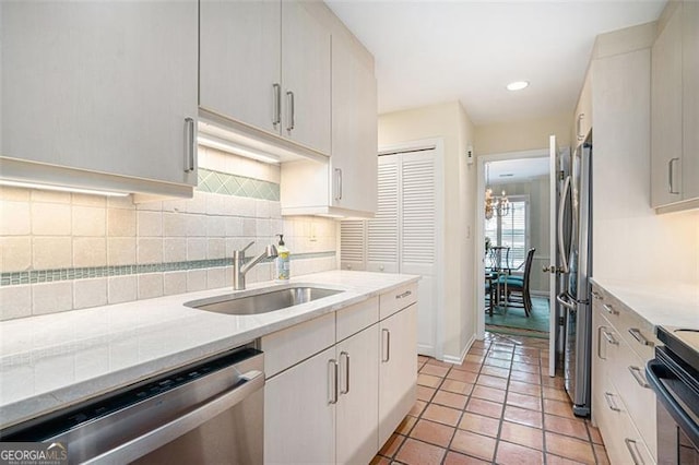 kitchen featuring light tile patterned flooring, appliances with stainless steel finishes, sink, white cabinets, and decorative backsplash