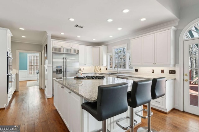 kitchen featuring a center island, a breakfast bar area, white cabinets, and light hardwood / wood-style flooring