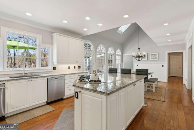 kitchen featuring appliances with stainless steel finishes, decorative light fixtures, sink, white cabinets, and a center island