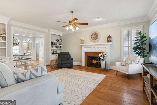 living room featuring crown molding, hardwood / wood-style floors, a wealth of natural light, and a fireplace