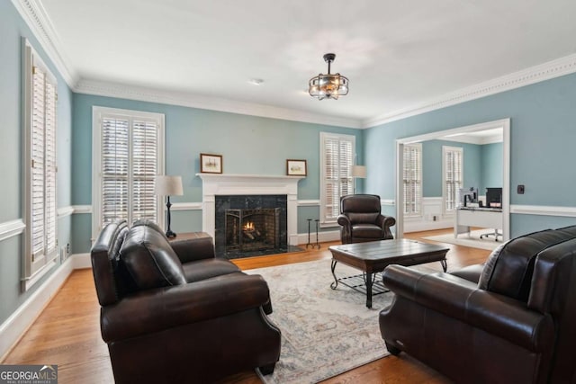 living room with crown molding, a healthy amount of sunlight, a high end fireplace, and light hardwood / wood-style flooring