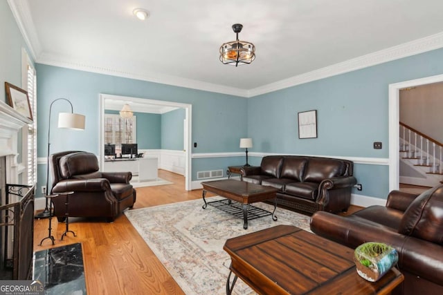 living room featuring crown molding, light hardwood / wood-style flooring, and a premium fireplace