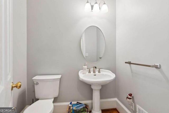 bathroom featuring an inviting chandelier and toilet