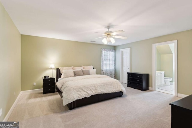 bedroom featuring ceiling fan, light colored carpet, and ensuite bath