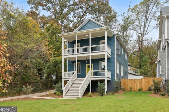 view of front of house with stairway, covered porch, a front lawn, and a balcony