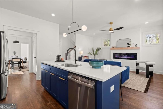 kitchen with dark wood finished floors, blue cabinetry, appliances with stainless steel finishes, and a sink