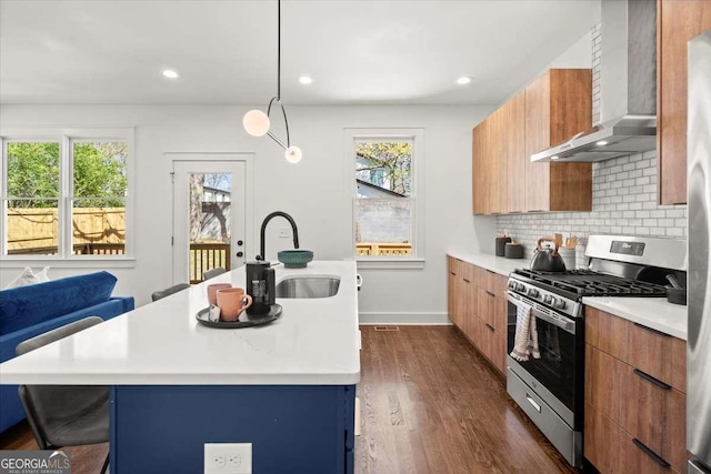 kitchen with modern cabinets, a sink, tasteful backsplash, wall chimney exhaust hood, and gas range