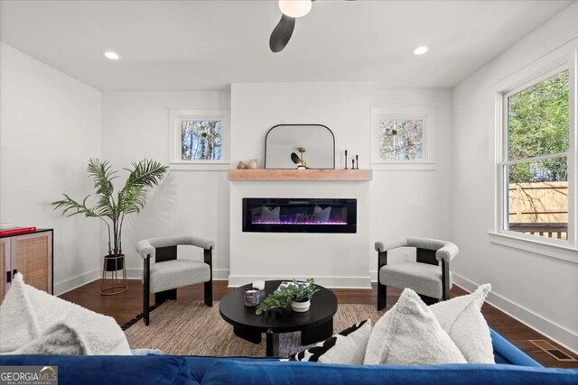 living area featuring a glass covered fireplace, recessed lighting, baseboards, and wood finished floors