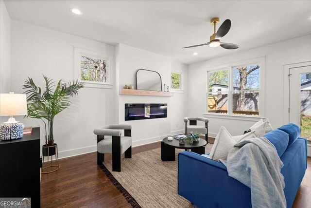 living area featuring baseboards, recessed lighting, wood finished floors, a glass covered fireplace, and a ceiling fan