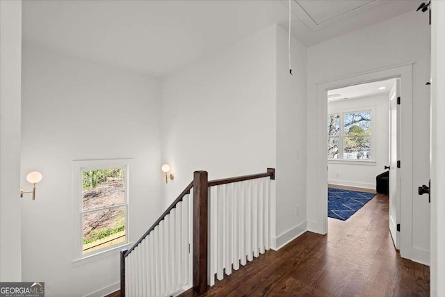 hall featuring an upstairs landing, plenty of natural light, baseboards, and wood finished floors
