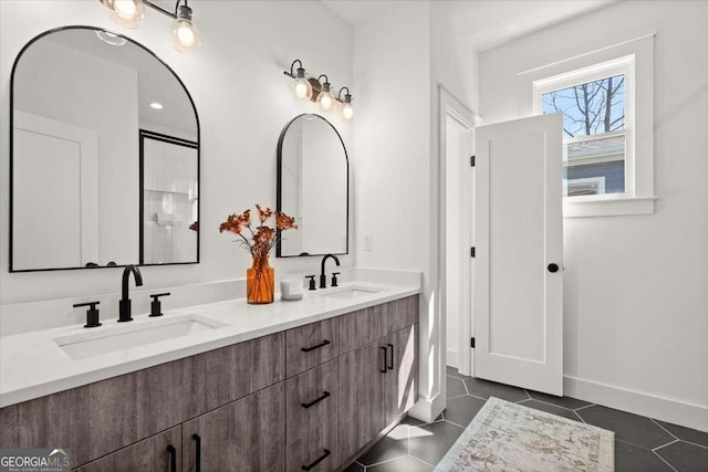 full bath with tile patterned floors, double vanity, baseboards, and a sink