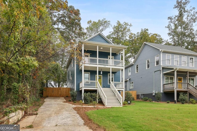 view of front of property featuring a front lawn, a balcony, stairway, and covered porch