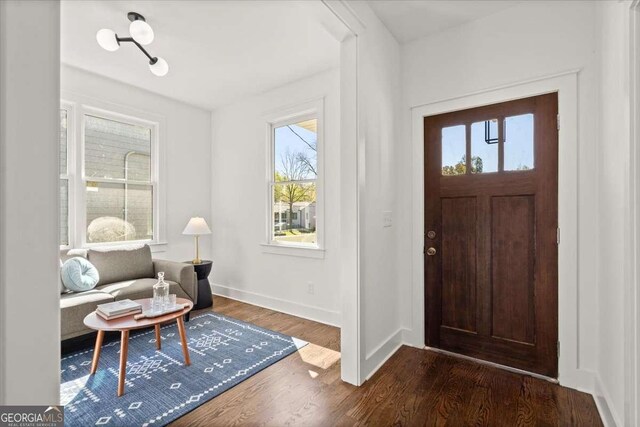 foyer with dark wood-type flooring and baseboards