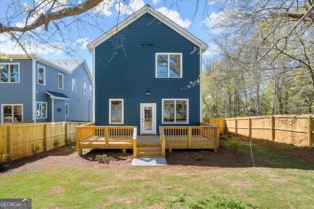 rear view of property featuring a wooden deck, a lawn, and a fenced backyard