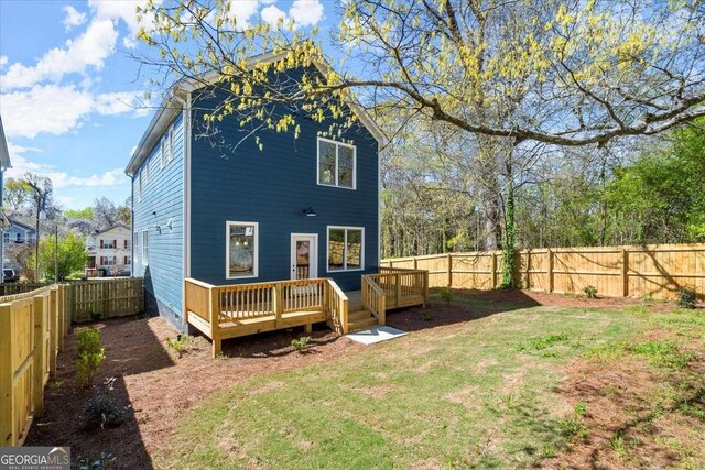 back of house with a deck, a fenced backyard, and a lawn