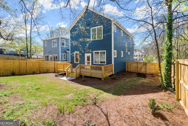 rear view of property with a deck, a fenced backyard, and a lawn