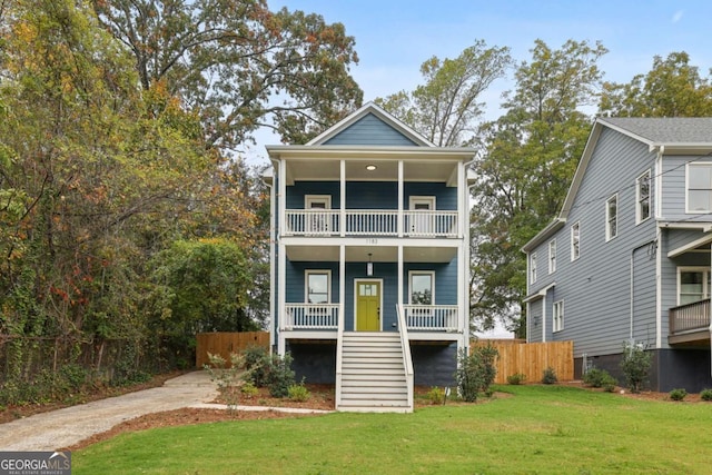 view of front of home featuring a front lawn, fence, covered porch, a balcony, and stairs