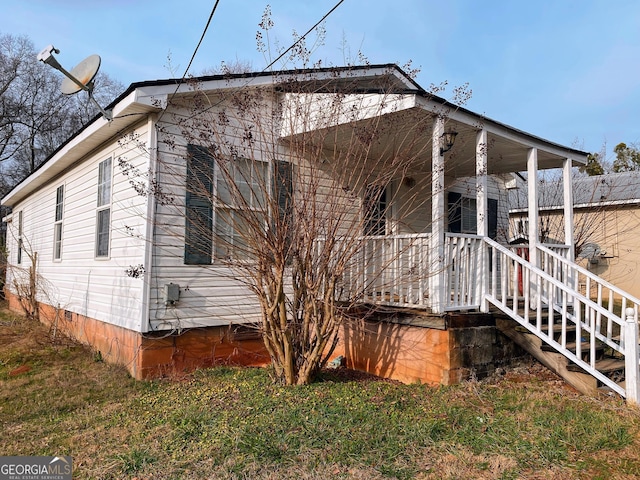 view of side of property with a porch and a lawn