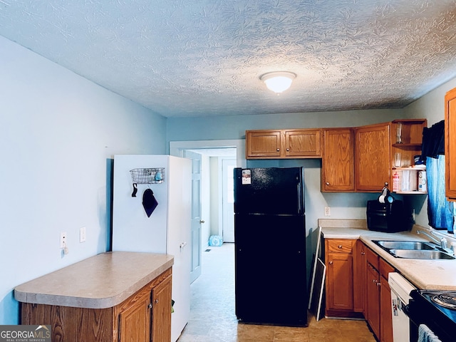 kitchen featuring black refrigerator, sink, a textured ceiling, and dishwasher