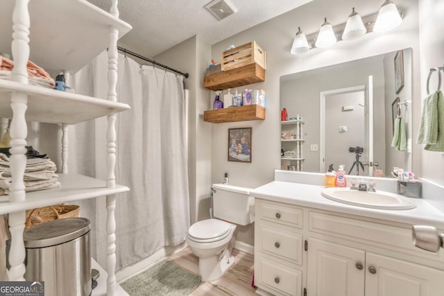 bathroom with hardwood / wood-style flooring, vanity, a textured ceiling, and toilet