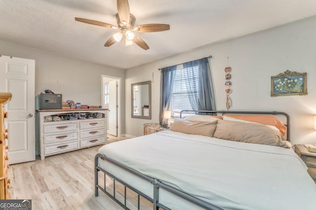 bedroom featuring ceiling fan, light hardwood / wood-style flooring, and a textured ceiling