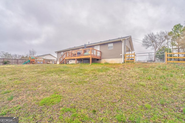 rear view of property featuring a playground, a yard, and a deck