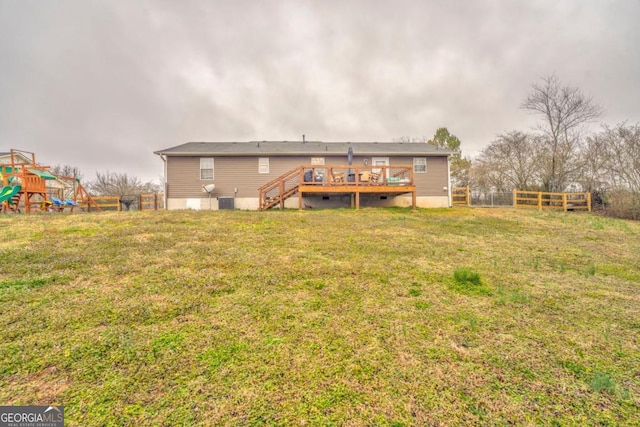 back of house featuring a playground, a yard, a deck, and central air condition unit