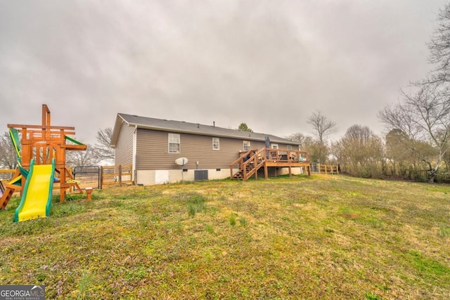 back of property featuring a playground, a deck, and a lawn