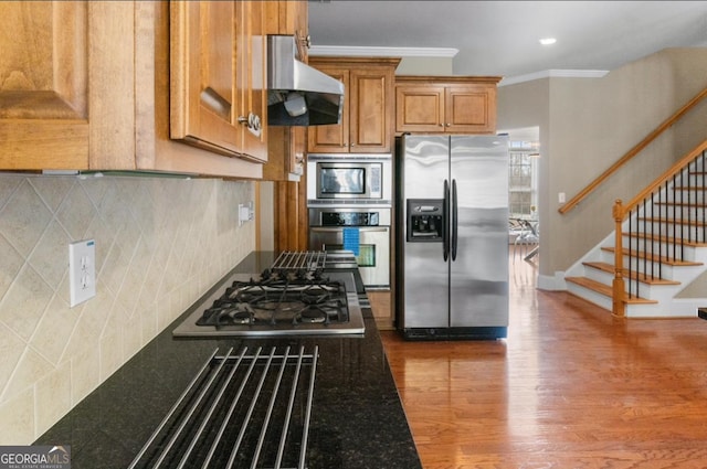 kitchen featuring hardwood / wood-style floors, range hood, backsplash, ornamental molding, and stainless steel appliances