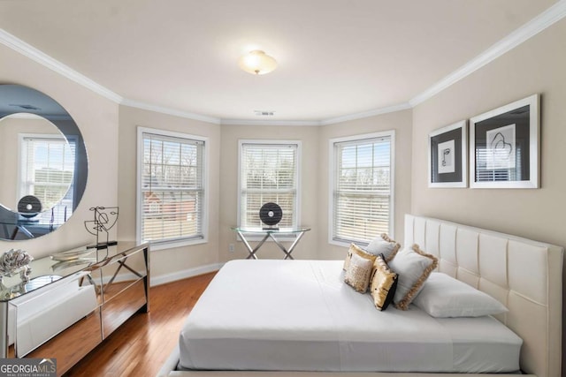 bedroom with hardwood / wood-style flooring, ornamental molding, and multiple windows